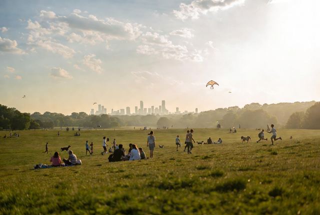 2:10 PM • Prospect Park, Brooklyn — Long Meadow Joy: Families and friends picnic across the sweeping green meadow with hazy Manhattan skyline watching over.