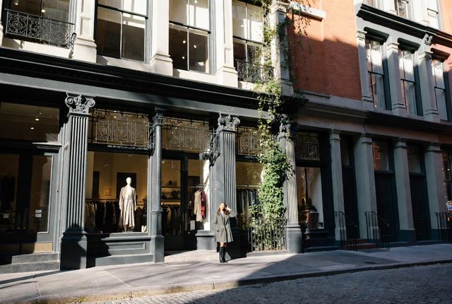 10:55 AM • SoHo, Manhattan — Cast Iron Light: Stylish woman pauses in front of a beautiful ivy-covered cast iron building on cobblestone streets in historic SoHo.